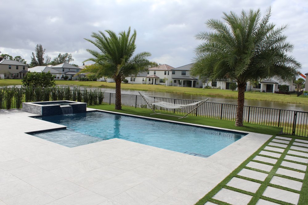 Lakeside swimming pool with white stone deck and palm trees