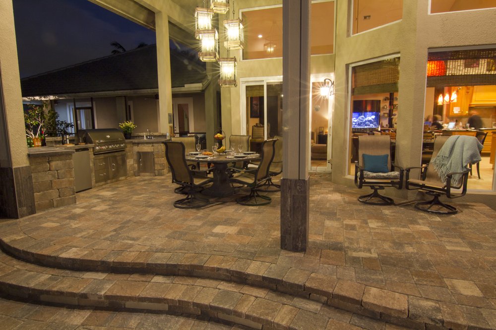 Covered outdoor kitchen with stone pavers and dining area