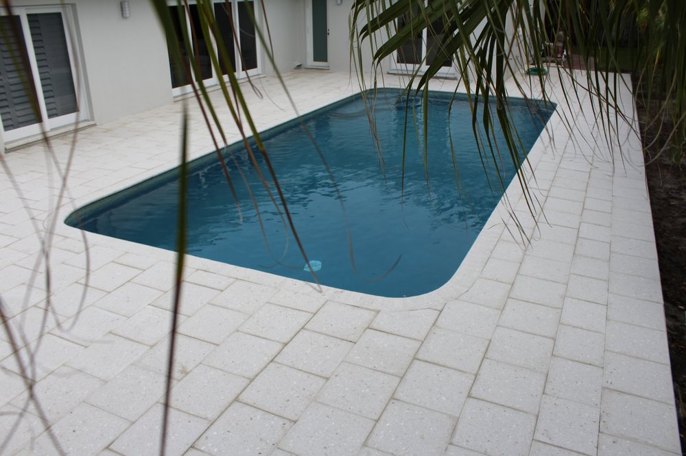 White stone pavers surrounding a swimming pool